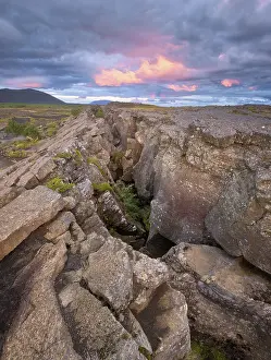 Icelandic Geology Drucke: Red column in the plain with dramatic clouds in the evening sky in the fault zone