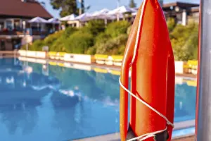 Reflective Water Surface Drucke: A red life preserver is on a ledge next to a pool