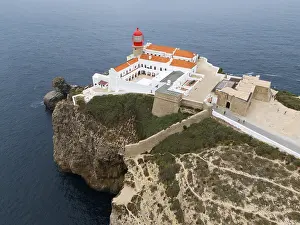 Portuguese Coastal Scene Drucke: A red lighthouse on a cliff above the ocean