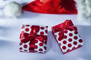 Christmas Gift Box Drucke: Red Santa hat wrapped present box on white surface