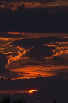 Deserted Evening Atmosphere Drucke: Red sun behind clouds in the evening sky