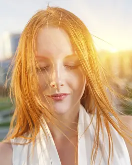 Contemplative Young Woman Drucke: Redhead backlit by the sun. Closed eyes
