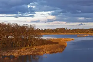 Wetland Biotope Germany Drucke: Reflecting river with reed vegetation in the soft light of a dramatic sunset