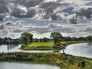 European River Landscape Photography Drucke: River landscape with lighthouse and windmill under a cloudy sky