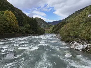 Serene River Drucke: A river with a lot of rocks and trees in the background