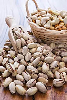 Atmospheric Landscape Photos Drucke: Roasted and salted pistachios and nuts over a rustic table in backlit