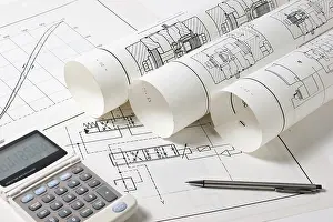 Construction Project Management Drucke: Rolled technical drawings and a calculator