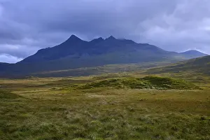 Overcast Sky Britain Drucke: Rolling meadows in front of a massive mountain under dark clouds