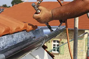 Close Up Gutter Detail Drucke: Roofer doing tinsmith work on a gutter