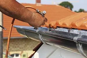 New Residential Building Construction Drucke: Roofer doing tinsmith work on a gutter