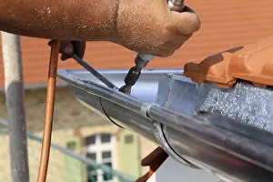Residential Building Construction Site Drucke: Roofer doing tinsmith work on a gutter