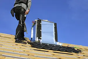 Construction Site Worker Drucke: Roofer works on the chimney cladding