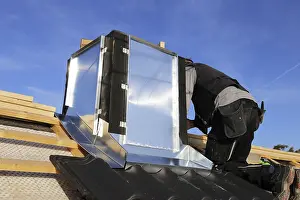 Construction Site Worker Drucke: Roofer works on the chimney cladding