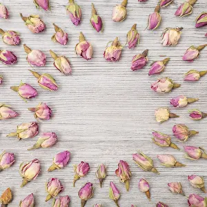 Collage Drucke: Runder Rahmen aus getrockneten rosa Rosenknospen auf Holzbrett.