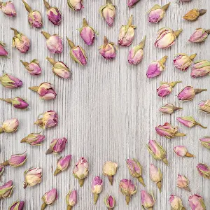 Collage Drucke: Runder Rahmen aus getrockneten rosa Rosenblütenknospen auf Holzplatte.