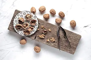 Wooden Board Arrangement Drucke: A rustic setup features whole and cracked walnuts on a patterned plate