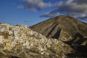 Colourful Mountain Village Drucke: A rustic village stretches beneath a mountainous backdrop with dramatic clouds