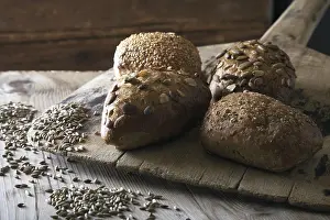 Rustic Still Life Photography Drucke: Rye bread rolls on an old bread slide with rye grains