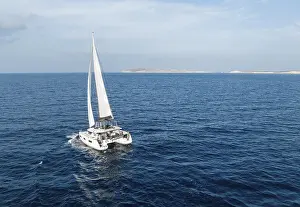Drucke von Ein Segelkater am Horizont, in voller Fahrt über das türkisblaue Wasser der Südaegeis Sport Drucke: Segelkater in vollem Segen, auf dem Meer im Südlichen Ägäischen Meer, Griechenland.