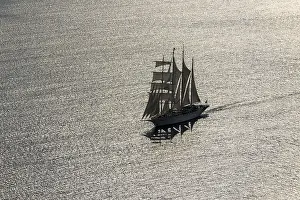 Drucke von Segelschiff im Hintergrundlicht auf Santorin, Santorin, Griechenland Sport Drucke: Segelschiff im Rücklicht auf Santorin.
