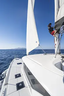 Sailing Catamaran Drucke: Sailor adjusts the sails on the mast