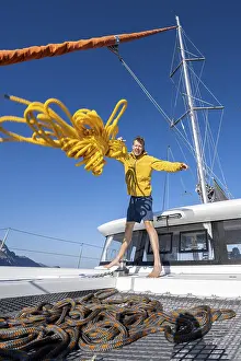 Drucke von Der Segler wirft einen gelben Seilstrang in Richtung der Kamera, während er auf einem Segelkatamaran segelt, Kos, Dodekanes, Griechenland Sport Drucke: Ein Seemann wirft einen gelben Strick in Richtung der Kamera.