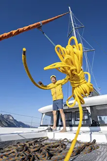 Sailing Catamaran Greece Drucke: Sailor throws a yellow rope towards the camera