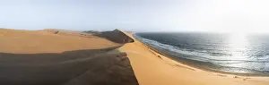 African Desert Scenery Drucke: Sand dunes with wave patterns and sea in evening light