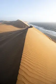 African Desert Landscapes Drucke: Sand dunes with wave patterns and sea in evening light