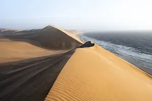 Sand Dunes Evening Light Drucke: Sand dunes with wave patterns and sea in evening light