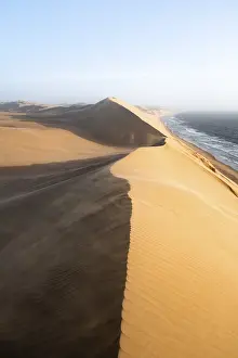 Barren African Landscape Drucke: Sand dunes with wave patterns and sea in evening light