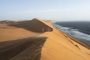 Windy Sand Dunes Africa Drucke: Sand dunes with wave patterns and sea in evening light