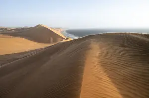 Natural Preserves Africa Drucke: Sand dunes with wave patterns and sea in evening light