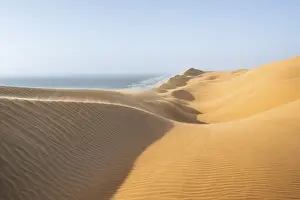 Impressive Desert Scenery Drucke: Sand dunes with wave patterns and sea in evening light