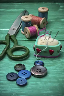 Female Tailor At Work Drucke: Scattering of buttons, thread and needle on turquoise background