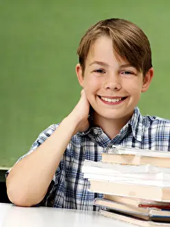 Schoolboy Portrait Drucke: Schoolboy in front of a school blackboard with a stack of books