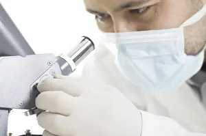 Man In Protective Suit Drucke: Scientist watches through a microscope