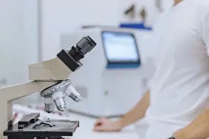 Laboratory Inspection Drucke: A scientist in a white shirt analyzes samples through a microscope in a modern laboratory setting