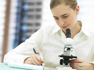 Female Scientist Microscope Drucke: Scientist working with a microscope