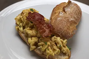 Close Up Scrambled Eggs Drucke: Scrambled eggs with fried bacon on a rustic roll