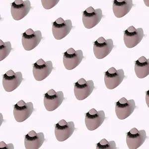 Pastel Color Decoration Drucke: A seamless pattern featuring makeup sponges adorned with false eyelashes set against a soft background