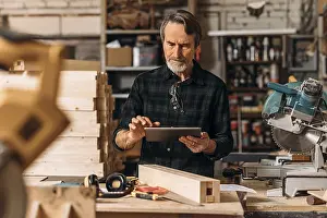 Male Craftsman Drucke: Senior carpenter using a digital tablet in his workshop