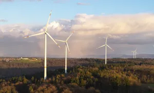 Cloudy Landscape Photography Drucke: A series of wind turbines in the forest against a dramatic backdrop of clouds in the sky