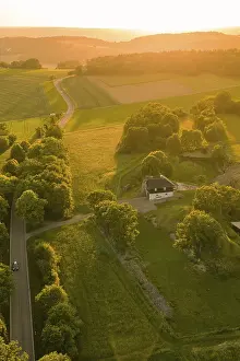 Black Forest Landscape Photo Drucke: Single building surrounded by fields and trees in golden sunlight