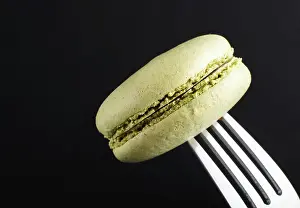 Close Up Cake Drucke: Single green macaron or macaroon cake on a fork on black background