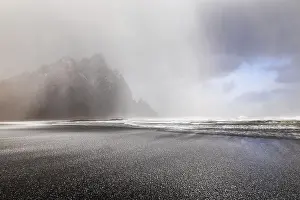 Volcanic Rock Formation Europe Drucke: Sleet on black lava sandy beach against mountain backdrop