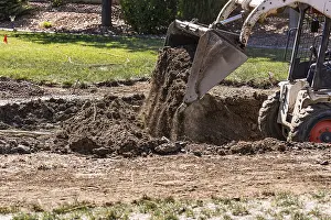 Pool Installation Process Drucke: Small bulldozer digging in yard for pool installation