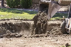 Real Estate Market Development Drucke: Small bulldozer digging in yard for pool installation