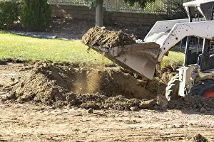 Agricultural Machinery Use Drucke: Small bulldozer digging in yard for pool installation