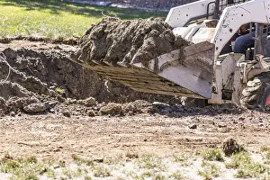 Swimming Pool Construction Drucke: Small bulldozer digging in yard for pool installation